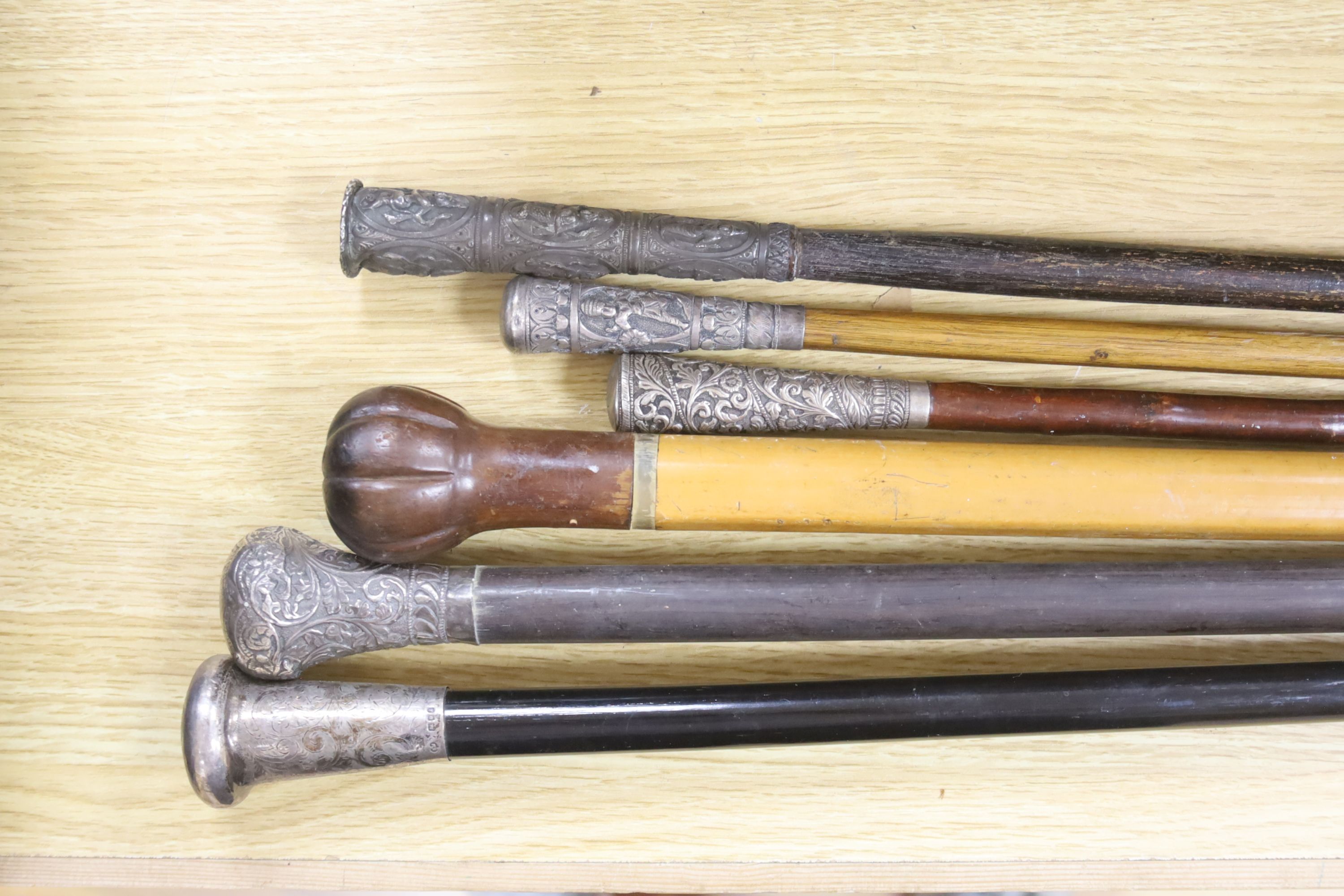 A set of six canes, one silver topped, four white metal and another